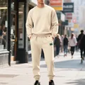 View of a man wearing a cream heavy fleece crewneck sweatshirt set on a city street - Apricot