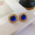 Détail de boucles d'oreilles vintage dorées avec pierre précieuse bleue ronde - Cercle Bleu