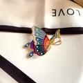 Close-up detail of a vintage enamel butterfly brooch with white pearls on a silk scarf - Vibrant Butterfly Dance