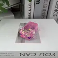 Vue détaillée d'un jouet antistress axolotl rose pailleté posé sur un livre - Axolotl Presse / Rose Métallique