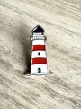 Macro view of a nautical lighthouse enamel pin featuring vibrant red and white stripes. - Lighthouse Design / 1.5x2.8cm