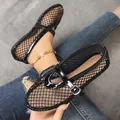 Gros plan sur des sandales plates en maille noire respirante avec une boucle métallique chic. - 36 / Noir