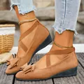 Dettaglio di scarpe marroni in camoscio con zeppa, fiocco e cinturini elastici incrociati - Marrone chiaro