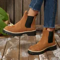 Close-up of brown suede platform Chelsea boots worn with denim jeans outdoors - Tan