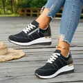 Close-up detail of women's black wedge sneakers featuring side zipper and gold trim. - 37 / Black