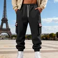 Black men's fleece cargo sweatpants with striped pocket detail in Paris street setting - Black