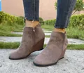 Close-up detail of taupe suede wedge ankle boots with side zipper on stone path - 35 / Gray