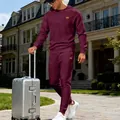 Detailed shot of a stylish men's burgundy crewneck jacquard knit tracksuit in travel setting - S / Top And Bottom / Burgundy