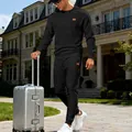 Outdoor street view of a man wearing a black jacquard knit sweatshirt and pants set. - S / Top And Bottom / Black