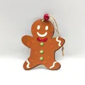 Detalle de un adorno navideño de madera con forma de hombre de jengibre y perla roja - Hombre de Jengibre de Navidad