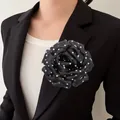 Detail of a chic French style black polka dot peony flower corsage on a black blazer - Black