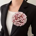 Elegant detail of a pink polka dot fabric peony flower brooch pinned on a black blazer jacket. - Coral