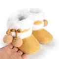 Close-up of cozy yellow baby boots featuring white faux fur lining and pom-poms - 11cm / Apricot