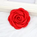 Makro-Detail einer 6 cm großen roten handgefertigten Satinrose für Kleidung und Haar. - Flache Basis / Rot