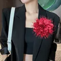 Elegante oversized rode stoffen bloembroche met kraalaccenten gedragen op een zwarte blazer - Bordeauxrood