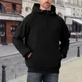 Close-up of men's black half-zip hoodie with front pocket in outdoor street setting. - S / Tops / Black