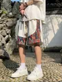 Detail view of men's white linen shorts with colorful ethnic pattern side panels - S / Bottoms / White