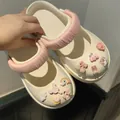 Gedetailleerd overzicht van crème Mary Jane klompen met roze bandjes en DIY-bedeltjes - Bedeltjes + Bandje Set / Roze Stijl