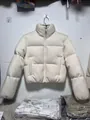 Close-up detail of a cream-colored knit fabric stand-collar puffer jacket for winter - XS / Tops / Apricot