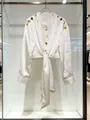 Detail van een witte satijnen blouse met gouden knopen en strikceintuur detail. - S / Tops / Wit