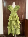 Elegante groene gelaagde avondjurk met ruches en plooien op een etalagepop voor display. - S / Dresses / Groen
