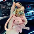 Detailed view of a pink crocheted bear keychain featuring a golden bell and braided strap - Knitted Bear Style (With Strap and Bell) / Pink