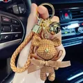 Detail of a brown crochet bear keychain with a leather strap in a car - Knitted Bear Style (With Strap and Bell) / Khaki