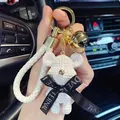 Macro view of a white textured bear keychain with a gold bell and decorative ribbon - Knitted Bear Style (With Strap and Bell) / White
