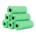 Detail view of stacked green plastic rolls of pet waste bags on a clean white background - 15 Count Per Roll / Green