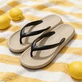 Sommerliche EVA-Zehentrenner in Beige mit schwarzen Riemen auf gelbem Handtuch - 35 / Khaki