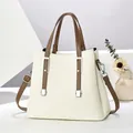 Elegante cremeweiße Handtasche aus Kieselleder mit braunen Trägern und Silberbeschlägen - Gebrochenes Weiß