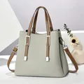 Elegante hellgraue Handtasche aus genarbtem Leder mit braunen Riemen und Metallteilen - Grau