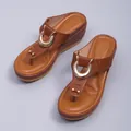 Gros plan de sandales compensées marron avec boucle dorée et motifs perforés élégants - Marron