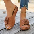 Detailed macro view of stylish brown wedge slippers featuring a large decorative flower - Brown