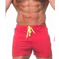 Close-up detail of red men's gym shorts featuring a vibrant yellow drawstring and elastic waist. - M / Bottoms / Red
