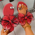 Close-up of elegant red toe-loop sandals featuring large mesh bows and crystal accents. - 38 / Red