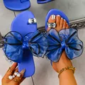 Détail des sandales plates bleues avec de grands nœuds en résille et strass - 38 / Bleu