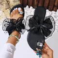 Detail of black summer flat sandals featuring a large mesh bow and rhinestone toe ring. - 38 / Black