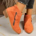 Close-up of stylish orange suede ankle boots featuring double zippers and a low chunky heel. - 36 / Orange