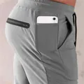 Close-up of men's gray sports joggers featuring a dedicated side phone pocket and zip pocket - M / Bottoms / Light Gray
