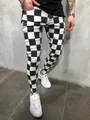 Close-up of black and white checkered men's skinny sports pants in an urban setting - M / Bottoms / Checkered