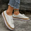 Detailed view of white platform loafers with tassels and perforated design on a stone path - White