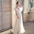 Elegant white lace evening gown featuring deep V-neck and flared sleeves in a romantic outdoor setting. - S / Dresses / White