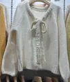 Dettaglio di un cardigan in maglia bianca con chiusura a fiocco in pizzo floreale - Taglia unica (40-62.5kg) / Top / Bianco