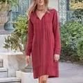 Close-up of a retro red long-sleeved V-neck midi dress with tie strings in a garden. - Red