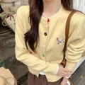 Detailed view of yellow knitted cardigan with colorful buttons and dog embroidery. - One Size / Tops / Yellow
