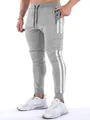 Close-up of grey men's sports joggers with white side stripes and multi-pocket detail - S / Bottoms / Light Gray