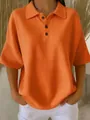Close-up of bright orange waffle knit polo shirt for women with button detailing - Orange