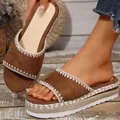 Detailopname van bruine suède wedge sandalen met een platform van gevlochten jute touw. - Bruin
