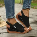 Close-up detail of women's black wedge sandals with fashion label and white stitching - 36 / Black